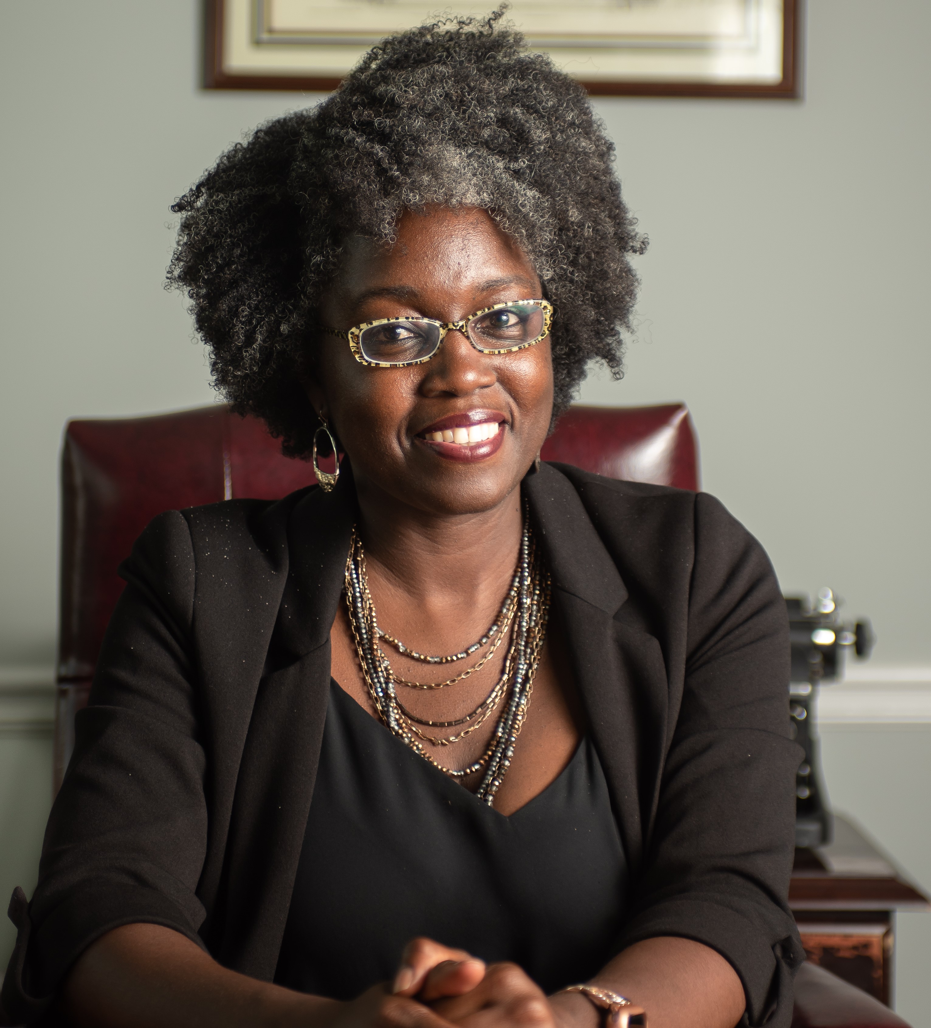 Jasmine Clark sitting at a desk in a black top and black blazer